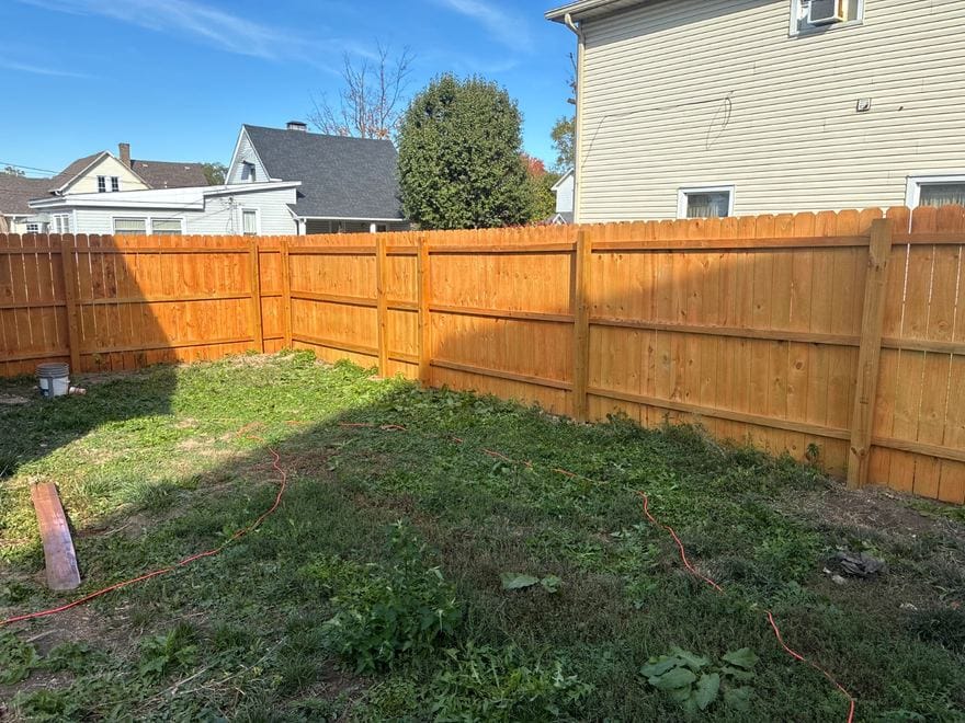 Treated wood privacy fence stained along a back yard