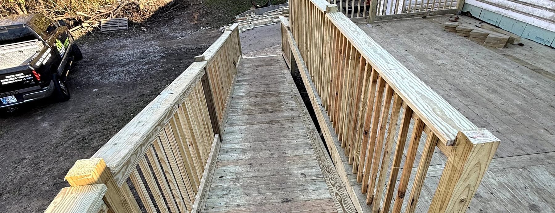 Wood deck with railing and stairs behind a house